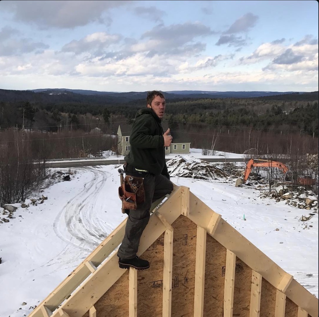 Paul standing at the peak of the first home he built